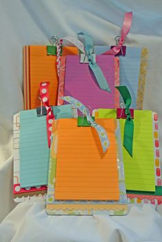 several colorful notepads are stacked on top of each other with ribbons attached to them