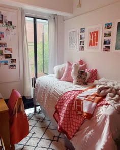 a bedroom with pink and white bedding, pictures on the wall, and a desk