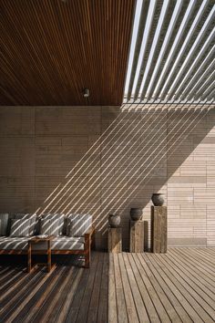 the sun shines on an outdoor lounge area with wood flooring and wooden slatted walls