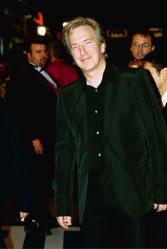 a man in a black suit and tie is walking down the red carpet at an event