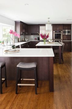 a kitchen with two stools and an island in the middle of the room,