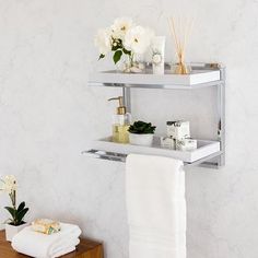 two shelving shelves with towels, candles and flowers on them in a white bathroom