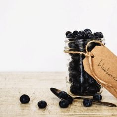 a jar filled with blueberries sitting on top of a wooden table