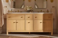 a bathroom vanity with two mirrors above it and a rug on the floor next to it