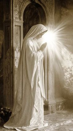 a woman dressed in white is standing with her hands together and looking at the light