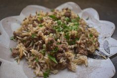 a plate full of rice with meat and green garnish on the top is ready to be eaten