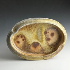 a ceramic bowl with four holes in the middle and brown glaze on it's surface