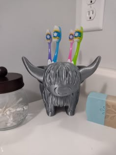 three toothbrushes sitting in a holder on a bathroom counter next to a soap dispenser