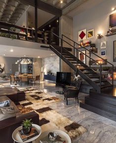 a living room filled with lots of furniture and a staircase leading up to the second floor