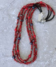 This appealing Necklace showcases 3 strands of Red Indonesian Glass Rondelle Beads. The Glass is opaque brick red in hue and approximately 3.5-by-4mm in dimension, with rounded edges and a matte finish. We've paired the Indonesian Glass with 7 complementary elements, including: Cranberry Czech Glass Faceted Rondelle Beads (8mm); Picasso Red Czech Tri-Cut Rounds (5-by-6mm); Shimmery Gray Glass Rondelle Beads (3-by-4mm); Polished Pyrite Rounds (4mm); Ruby Picasso Czech Glass Rounds (8mm); Red White Heart Glass Rondelle Beads (6.5-by-7mm); Translucent Red Cathedral-Cut Glass Rounds (5.5mm). These elements add color depth, translucency and subtle sparkle. At the top of the Necklace the Indonesian Glass transitions to 3mm Black Glass Seed Beads, streamlining the silhouette and ensuring a comfor Southwestern Red Beaded Necklace, Red Multi-strand Beaded Necklaces With Gemstones, Unique Red Multi-strand Beaded Necklaces, Red Southwestern Hand-strung Beaded Necklaces, Red Multi-strand Jewelry With Polished Beads, Southwest Design, Black Seed, Southwest Jewelry, Classic Necklace