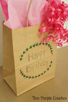 a brown paper bag with pink bows and the words happy birthday on it