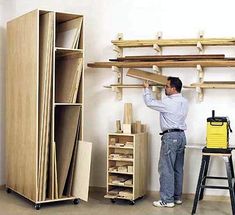 a man standing in front of a shelf filled with wooden shelves and ladders next to a workbench