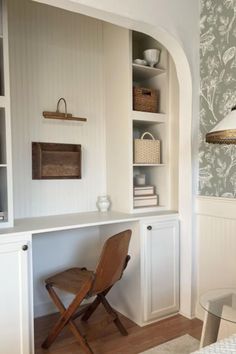 a chair sitting in front of a desk under a lamp next to a wall mounted bookcase