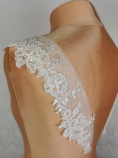 the back of a woman's wedding dress with white lace and flowers on it