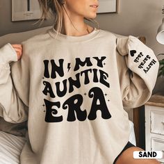 Looking for the perfect auntie gift? Look no further than our In My Auntie Era with names on Sleeve sweatshirt! This soft and comfortable sweater is ideal for any occasion.  And don't forget the kids! Our auntie sweatshirt is the perfect way to show your little ones that you love them with their names prominently displayed on the sleeve. Whether you're shopping for aunt, auntie or sister, our auntie sweatshirt is the perfect Mothers Day, birthday  or Christmas gift. So don't wait, order your sweater today! * S I Z I N G * ✺ Sizing is unisex  ✺ For adults, size runs like men's, though not overly large. Most women find their typical size works best, since they are meant to fit a touch loose and go up 1 or 2 sizes if you want the oversized look. ✺ Size guide and fit:  The size chart is listed Gift Ideas For Aunt, Aunt Sweater, Auntie Sweatshirt, Auntie Era, Photography Shirts, Cool Aunt, Ultrasound Tech, Little Sister Gifts, New Aunt