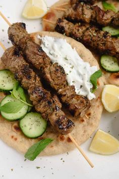 two skewered meats with cucumbers and sour cream on a pita