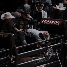 some people sitting in the back of a truck at a sporting event and one person is on his cell phone