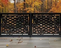 an open gate with autumn leaves on the ground and trees in the backround