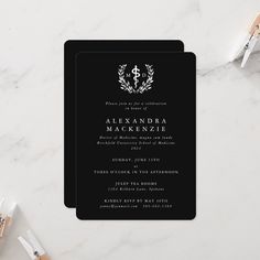 a black and white wedding card with an elegant monogrammed wreath on the front