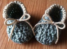 two crocheted baby booties are sitting on a wooden table with twine