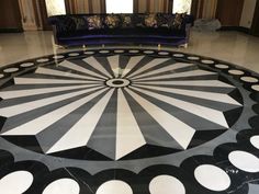 a black and white floor with circular designs on it in front of a blue couch