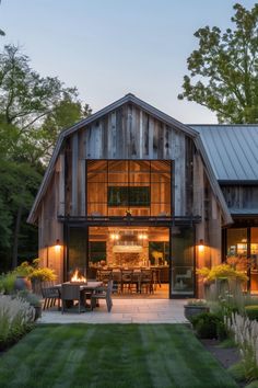 a barn house with an outdoor dining area in the front and side yard at dusk