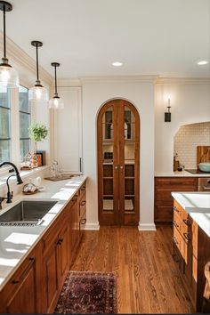 a kitchen with wooden cabinets and white counter tops next to a large open doorway that leads into the dining room