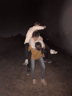 two men are hugging each other outside in the dark, one is holding another man