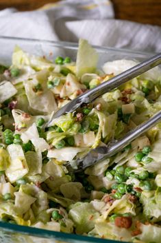 a salad with peas, lettuce and other toppings in a glass bowl