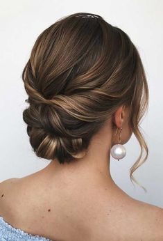 a woman with her hair in a low updo and pearls on the back of her head