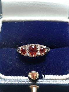 A vintage 9ct gold garnet and diamond ring. The ring is Hallmarked 9ct gold. The largest oval cut garnet is claw set at the centre and measures 5 x 4mms. The outside garnets each measure 4 x 3mm's. Flanking the central garnet on both sides are two round brilliant cut diamonds. These four diamonds have an estimated combined weight of 0.08ct's. Finger size N, but we can make the ring bigger, or smaller. Victorian Oval Red Diamond Ring, Victorian Style Red Oval Diamond Ring, Vintage Oval Three-stone Ruby Ring, Vintage Oval Garnet Birthstone Ring, Antique Red Oval Diamond Ring, Antique Oval Red Diamond Ring, Hallmarked Red Oval Sapphire Ring, Hallmarked Oval Red Sapphire Ring, Opal Drop Earrings