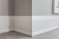 the corner of a room with white walls and wood flooring is painted in light gray