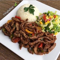 a white plate topped with meat and veggies on top of a wooden table