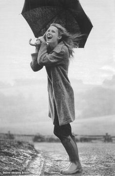 a woman holding an umbrella while standing in the rain with it's mouth open