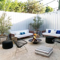 an outdoor living area with chairs, couches and a fire pit in the middle