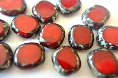 some red and black glass beads on a white surface