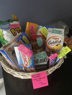 a basket filled with lots of different types of snacks and candy on top of a table