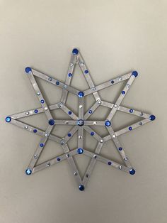 an ornament made out of metal and blue glass beads on a white wall