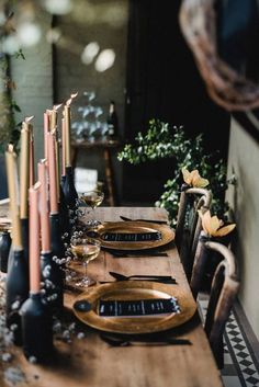 a wooden table topped with lots of plates and candles