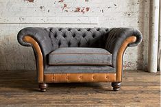 a grey and brown couch sitting in front of a brick wall