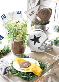 a football themed table setting with flowers and plates on the table, along with sports memorabilia