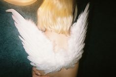 a woman with long blonde hair and white angel wings on her back, next to a clock