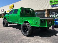 a green pick up truck parked in front of a building