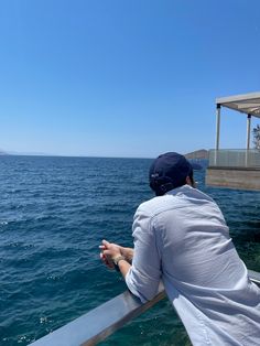 a man sitting on top of a boat looking out at the ocean