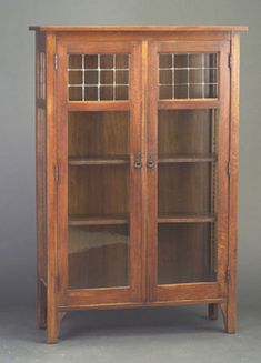 a wooden bookcase with glass doors on the front and bottom shelves, against a gray background