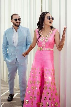 a man and woman standing next to each other in front of a white wall holding hands