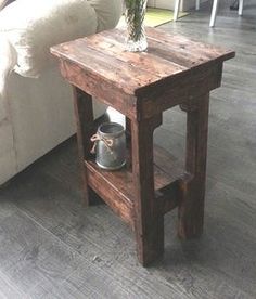 a small wooden table with a potted plant on it and a couch in the background