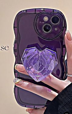 a woman holding up a purple case with a heart shaped object in the middle of it