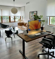 a desk with a computer on top of it in front of two chairs and a couch