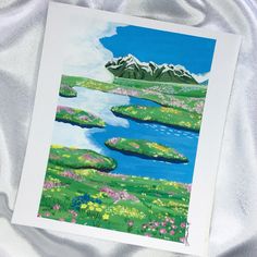 a card with a painting of a lake and mountains in the background on a white sheet